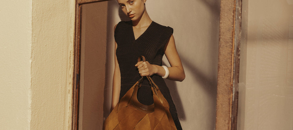 Eine elegante Frau in einem trägerlosen Kleid lehnt sich an einem Zaun an