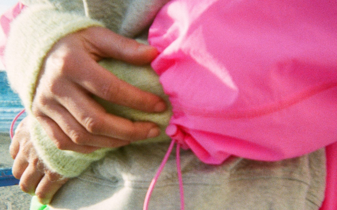 Ein Detailbild von Händen und einem Pullover mit bunter Jacke darüber