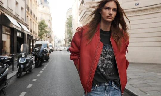 Ein weibliches, blondes Model trägt ein weißes T-Shirt und eine mittelblaue Jeans mit weitem Bein von Anine Bing