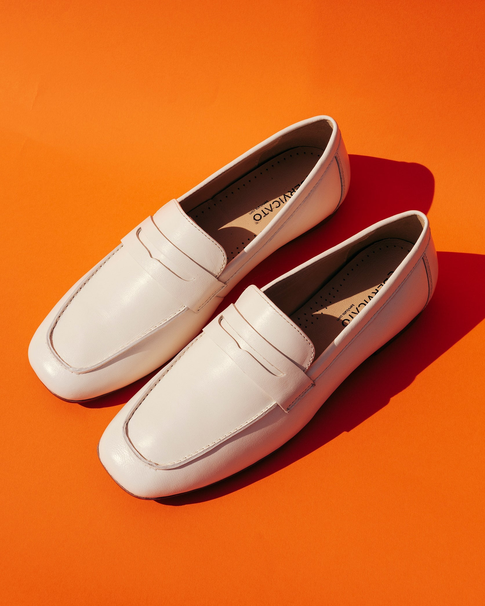 Ein weißer Stiefel steht auf einem braunen Sessel mit anderen Stühlen im Hintergrund