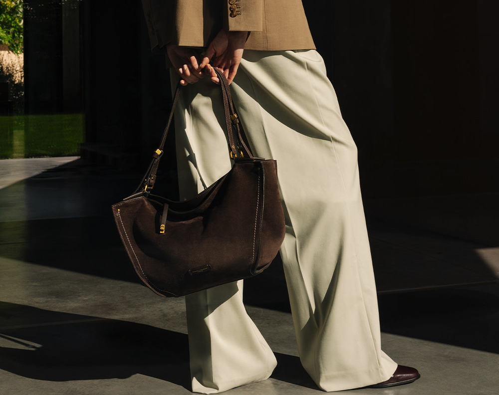 Eine elegante Frau in einem trägerlosen Kleid lehnt sich an einem Zaun an