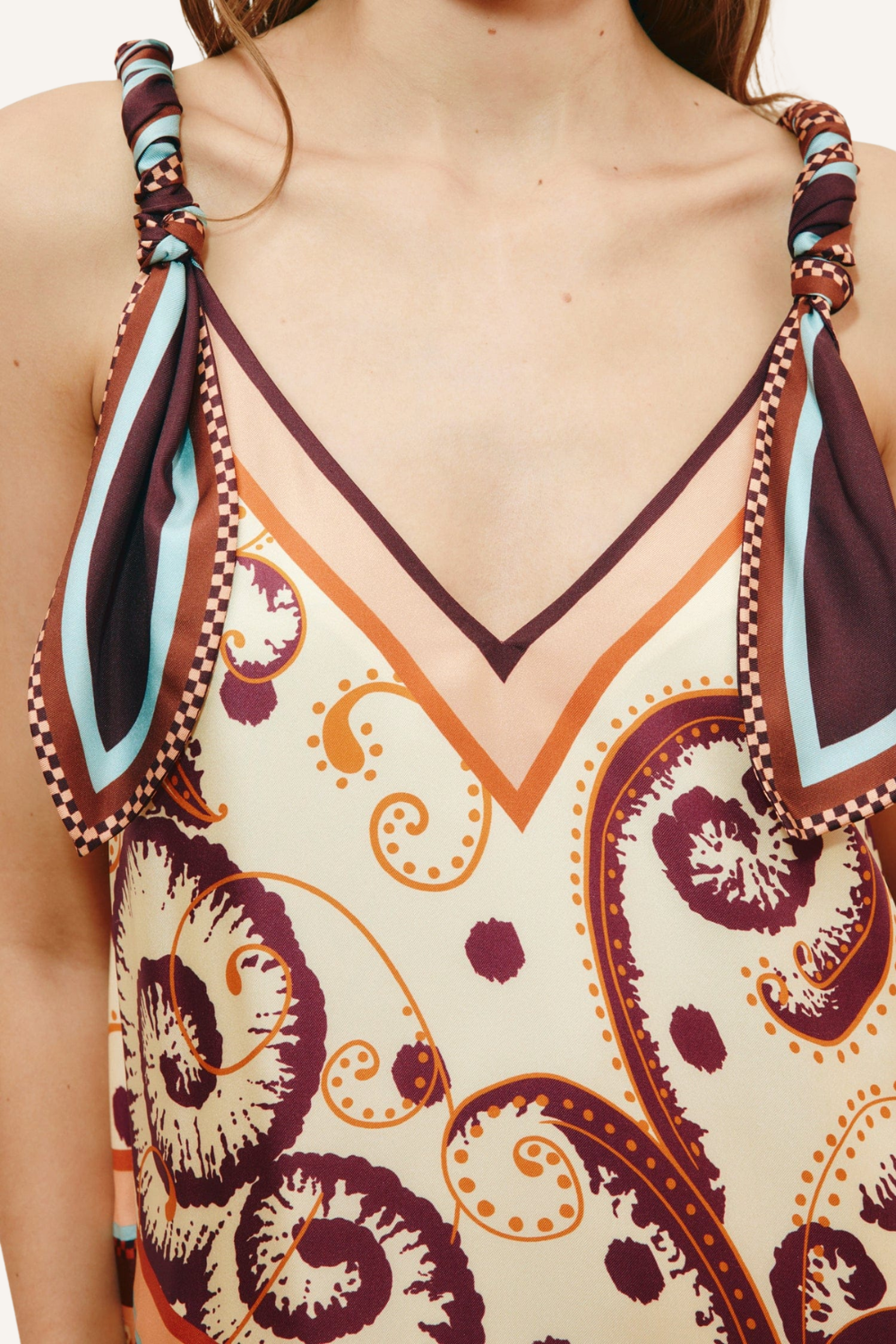 Close up: Frau trägt fließendes Midikleid mit Scarf-inspiriertem Muster, Twist-Detail an den Trägern zum Binden, femininem V-Ausschnitt und asymmetrischem Taillenverlauf aus leicht fallendem Seidentwill