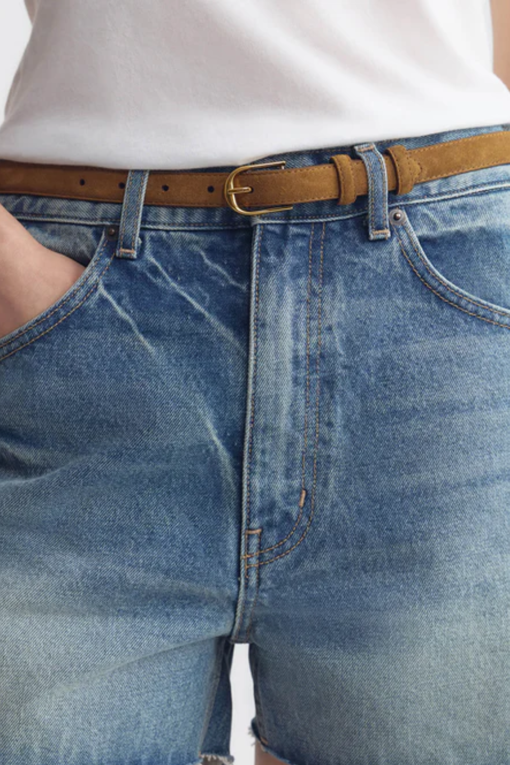 Schmaler 25 mm Gürtel mit bombiertem Finish und goldfarbener Schnalle an blauen Jeans mit hohem Bund
