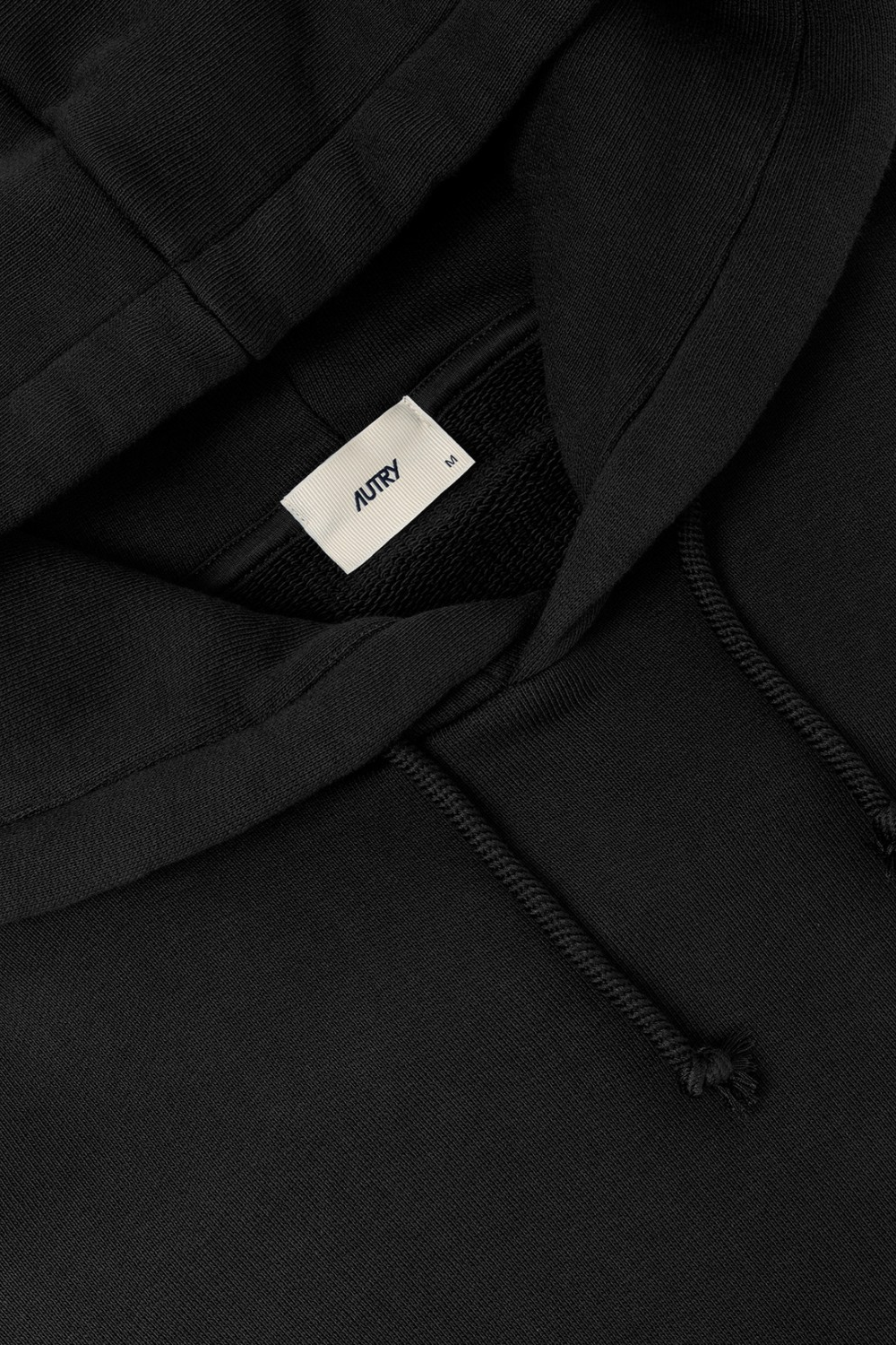 Close up: Schwarzer Hoodie aus ungebürstetem Sweatshirtstoff mit Kapuze, Kordelzug mit Metallösen, gerippten Bündchen und Saum sowie "Floating Dreams" Stickerei auf der Brust in Ton-in-Ton Optik