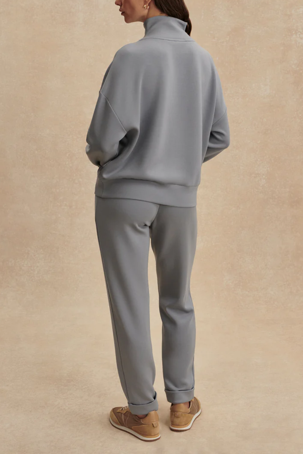 Frau trägt oversized Fit Sweatshirt mit halbem Reißverschluss, tiefen Ärmelbündchen und breitem Saumbund in babyblau