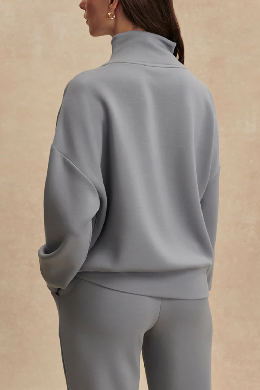 Frau trägt oversized Fit Sweatshirt mit halbem Reißverschluss, tiefen Ärmelbündchen und breitem Saumbund in babyblau
