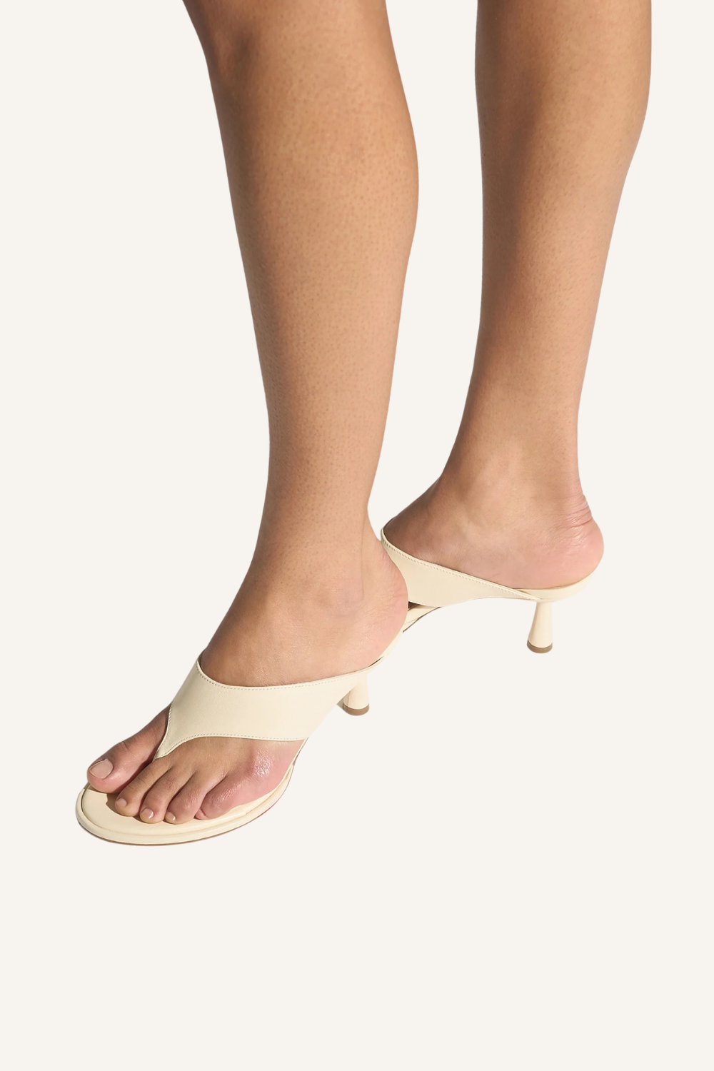 Füße mit eleganter Zehensandale mit breitem V-förmigem Riemen und kantigem Stiletto-Absatz