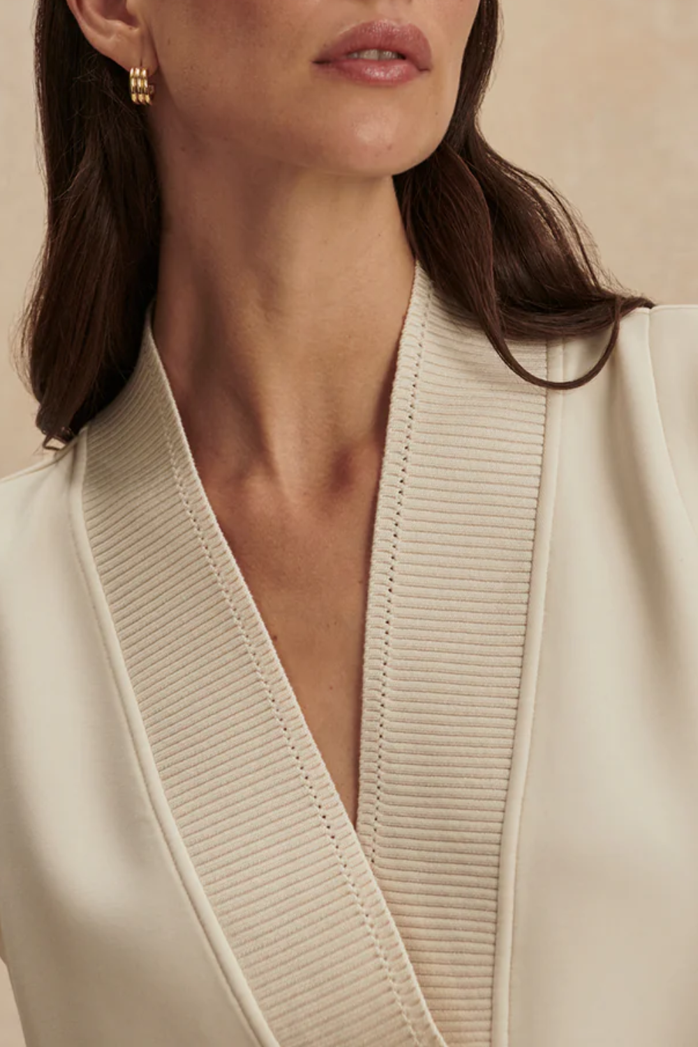 Ärmelloses Sweat-Top in Longline-Silhouette mit tiefem V-Ausschnitt, breitem Pointelle-Strickbündchen und seitlichen Schlitzen, getragen von einer Frau in entspannter Passform