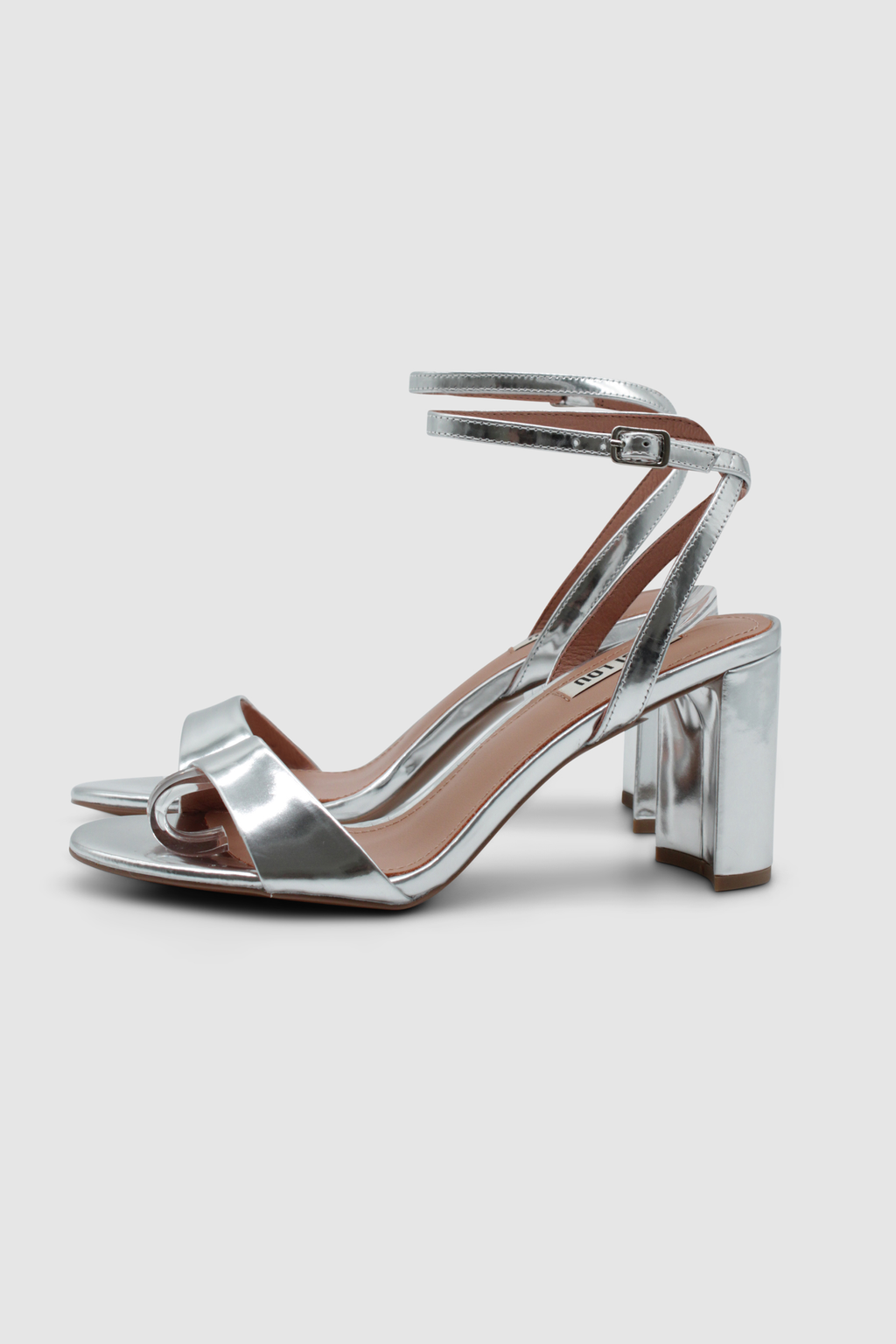 Silberne Sandalen mit einem Fesselriemen, der an der Ferse gekreuzt ist. Mit einem hohen, breiten Absatz. Von der Marke Bibi Lou