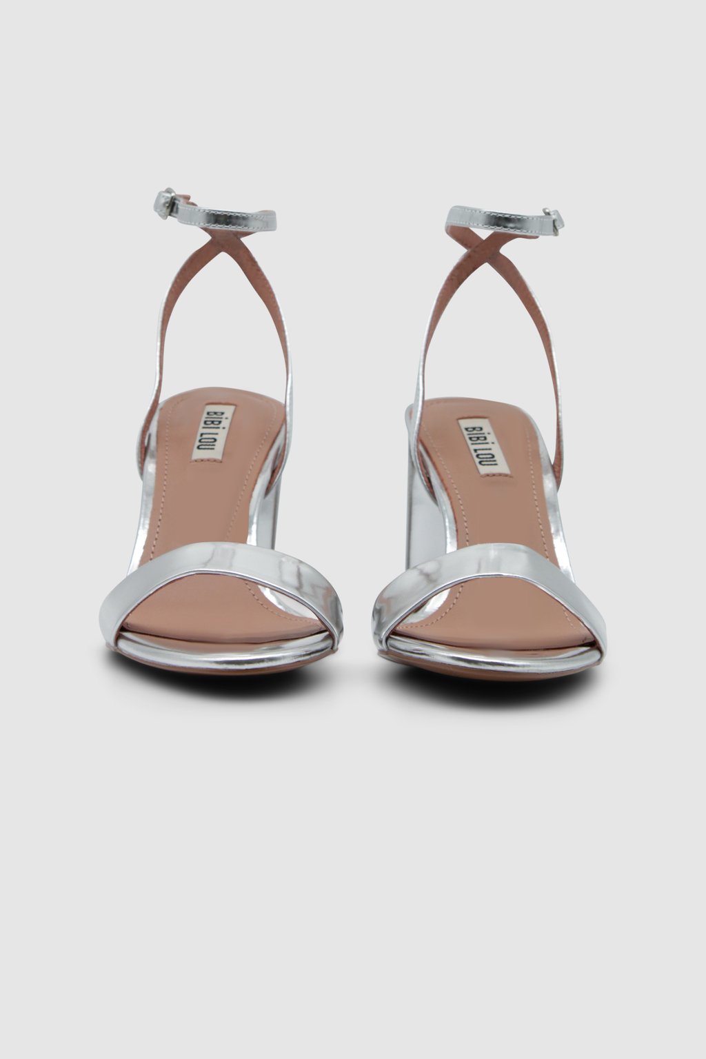 Silberne Sandalen mit einem Fesselriemen, der an der Ferse gekreuzt ist. Mit einem hohen, breiten Absatz. Von der Marke Bibi Lou