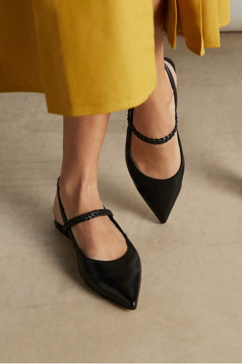 Close-Up von Modelfüßen in schwarzen, spitzen Slingballerinas. Das Model trägt einen gelben Rock