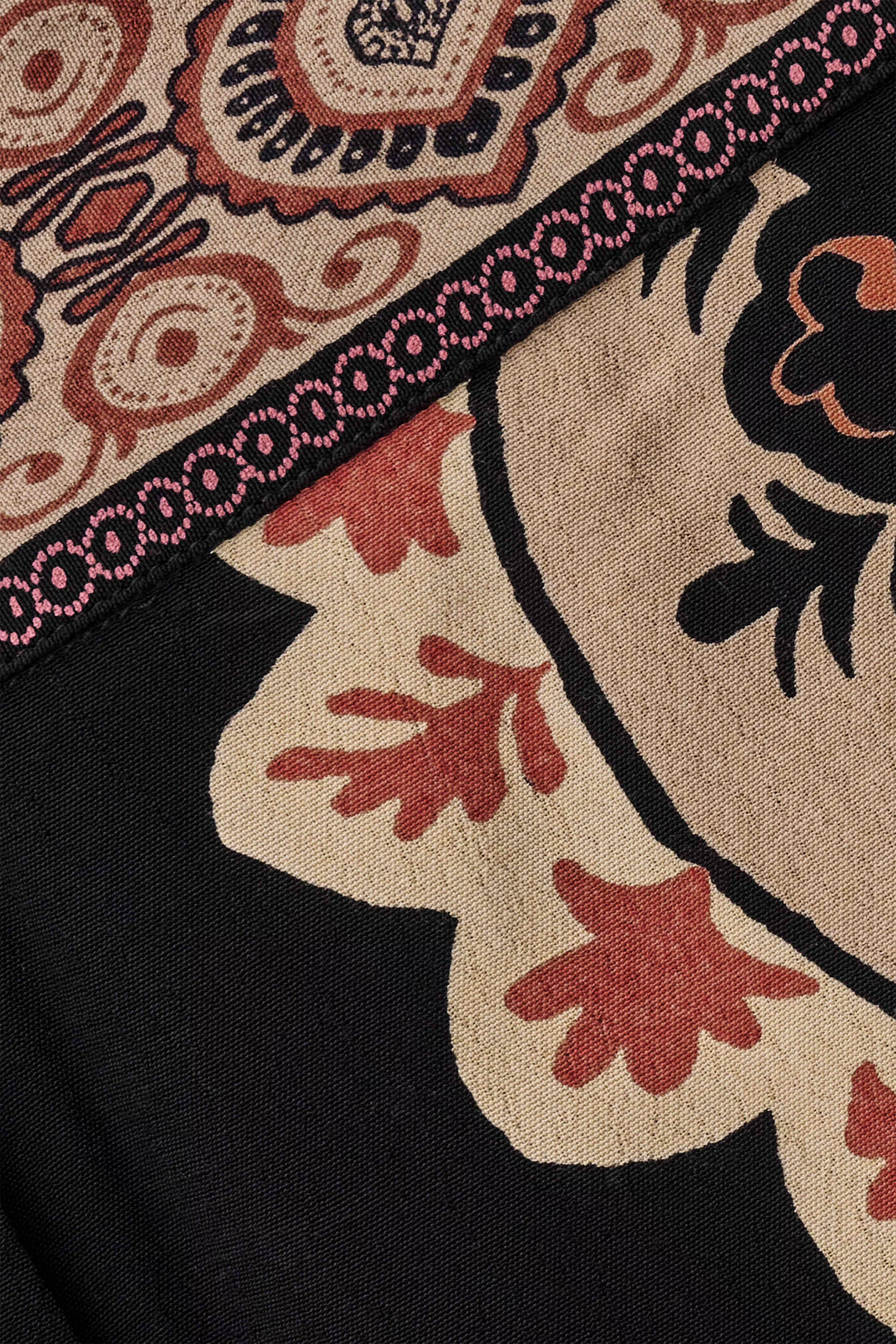 Close up: Schwarze ausgestellte Hose mit großen, runden Patches und gedruckten Streifen an den Seiten im Boheme-Stil