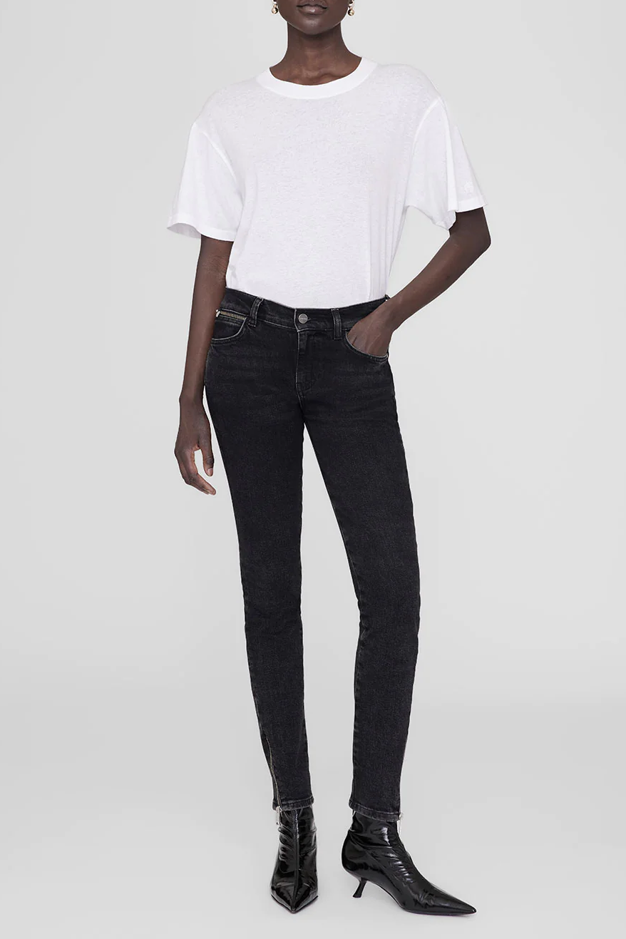Eine Frau trägt schwarze Jeans und ein weißes T-Shirt
