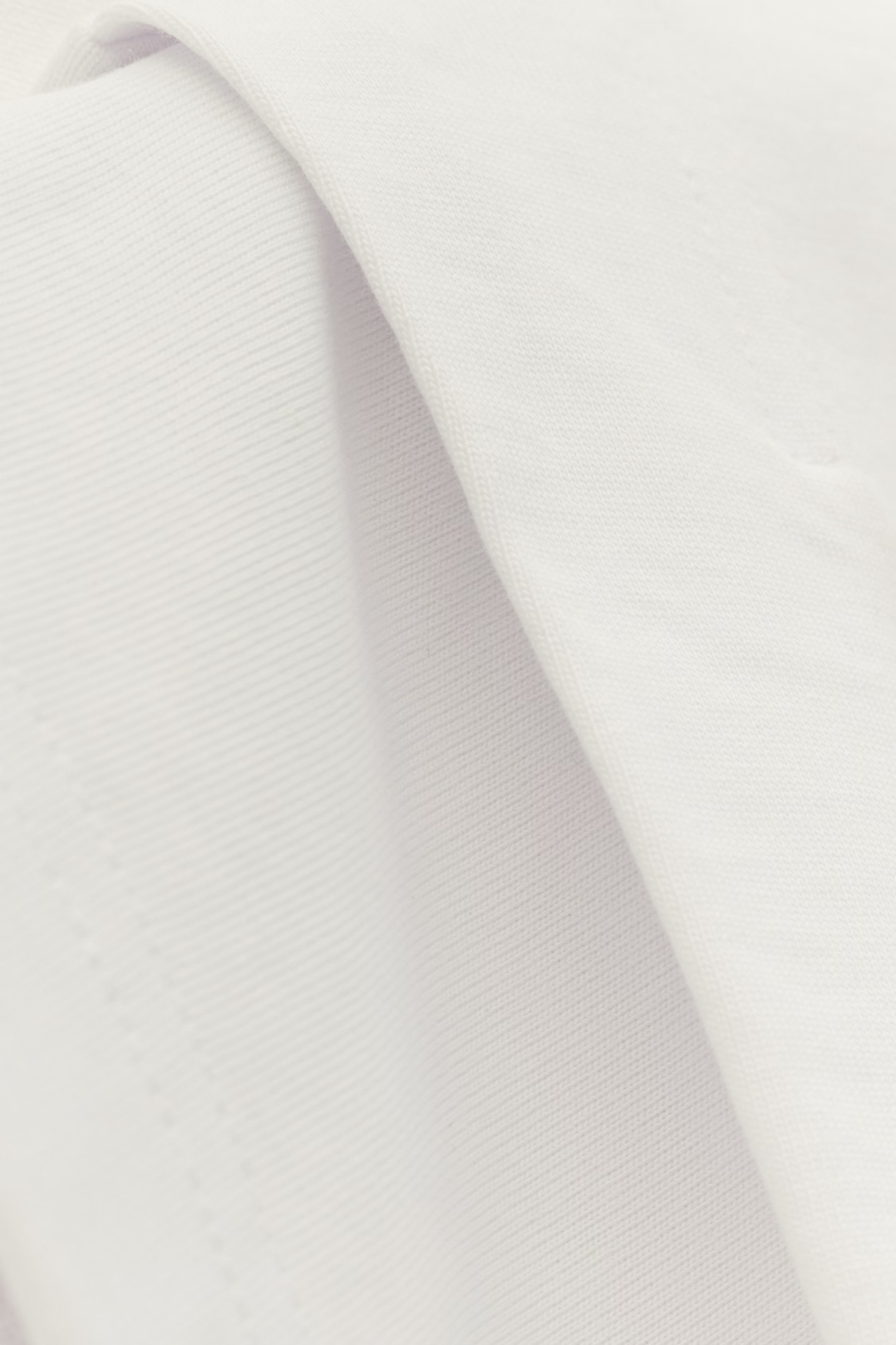 close up: Schlichtes weißes T-Shirt mit kurzem Ärmel und Rundhalsausschnitt, mit dem Label 'ba&sh' im Nackenbereich