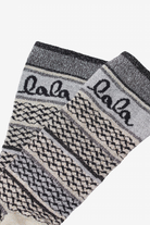 Detailfoto von rin Paar Socken mit einem weiß-schwarzen Muster und einem "lala" Schriftzug