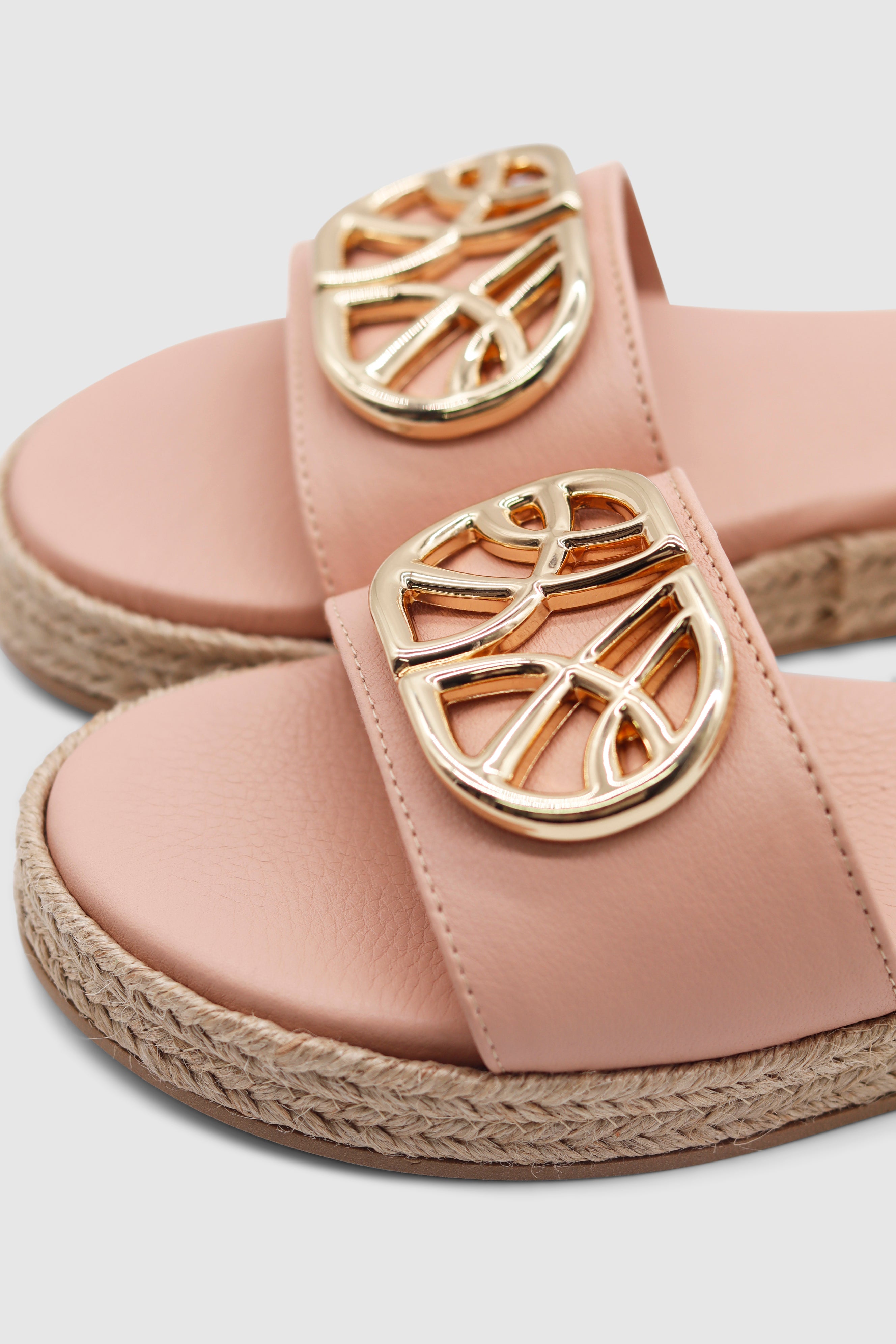 Eine Nahaufnahme von einem Paar rosa Sandalen mit einer goldenen Schnalle